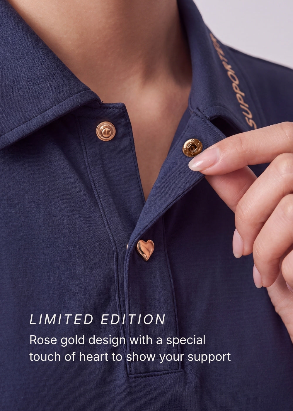 Limited edition navy blue polo shirt featuring rose gold snap buttons, a heart button, and 'SUPPORTER' collar text.