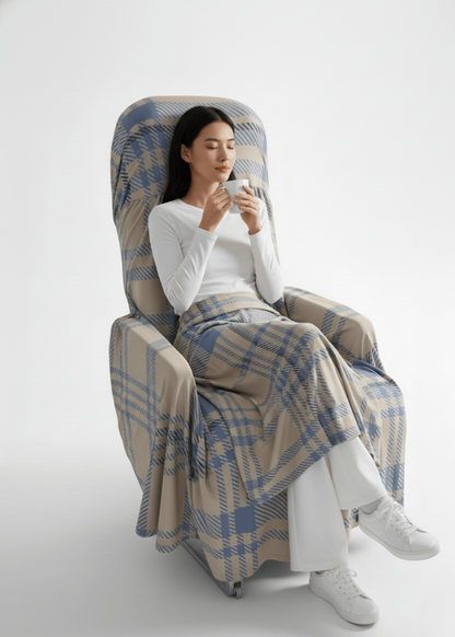 A model sitting comfortably on a seat covered with the travel set seat cover, wrapped in a multi-use sheet, and holding a mug — showing a cozy and relaxing travel experience.