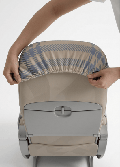 Two hands inserting the seat cover into a headrest.