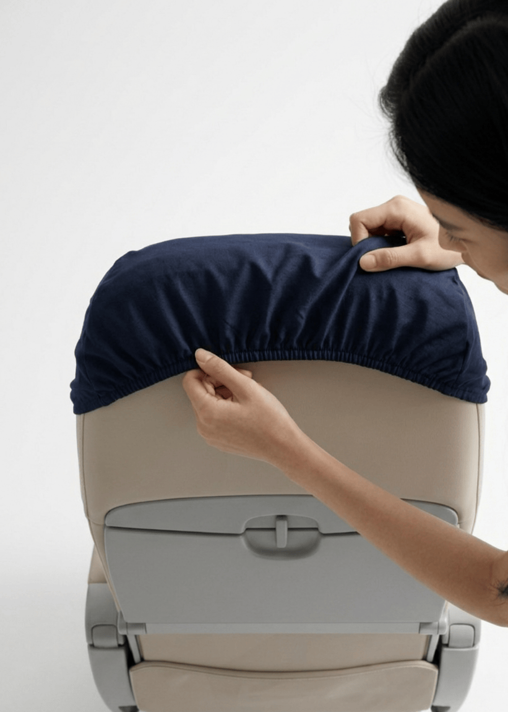 Two hands inserting the seat cover into a headrest.