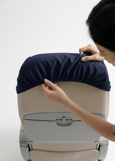 Two hands inserting the seat cover into a headrest.